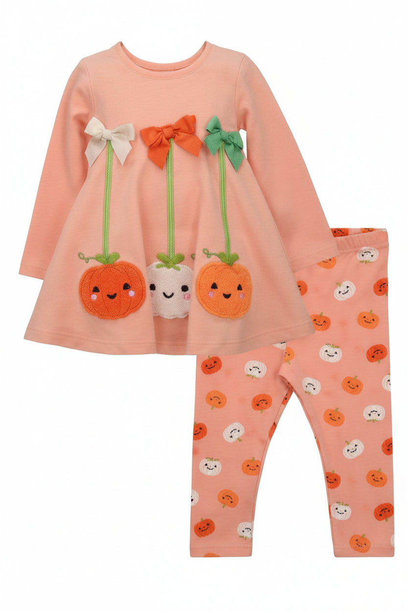 A toddler girl's two-piece set featuring a peach long-sleeve dress with pumpkin appliques and matching patterned leggings.