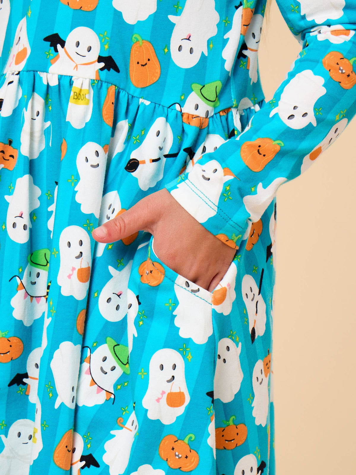 Close up of ghost and pumpkin pattern decorating an aqua striped dress