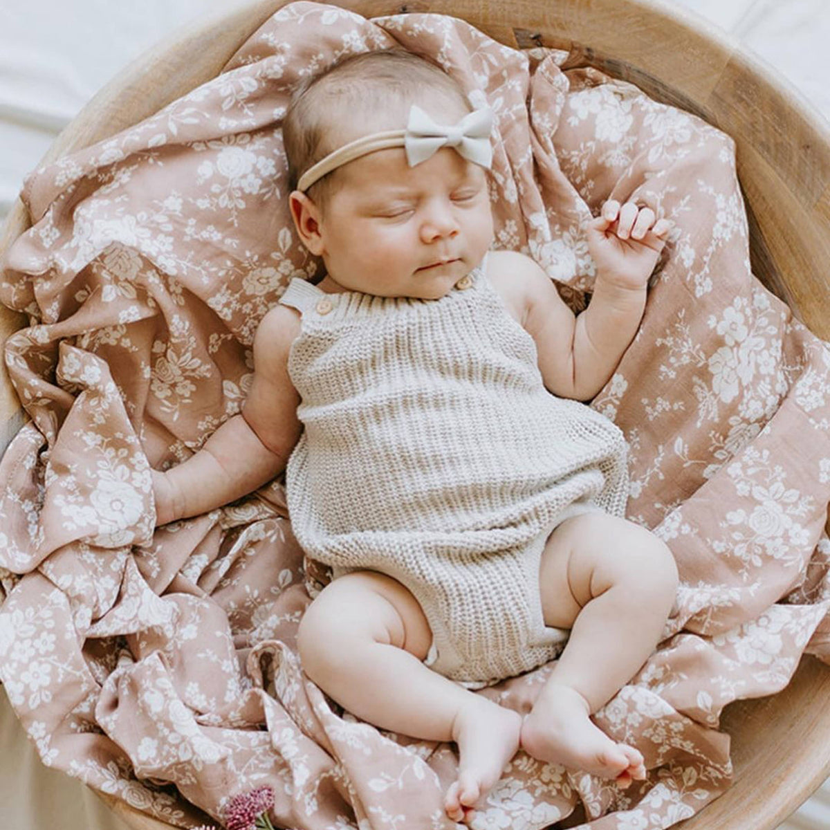 Newborn baby sleeping in a wooden basket with pink floral blanket