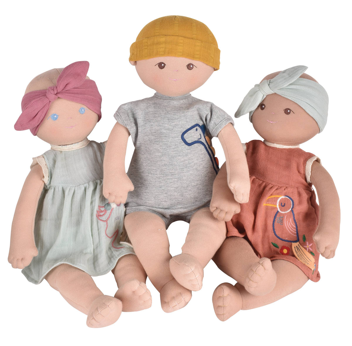 Three soft baby dolls sit together against a white background. 
