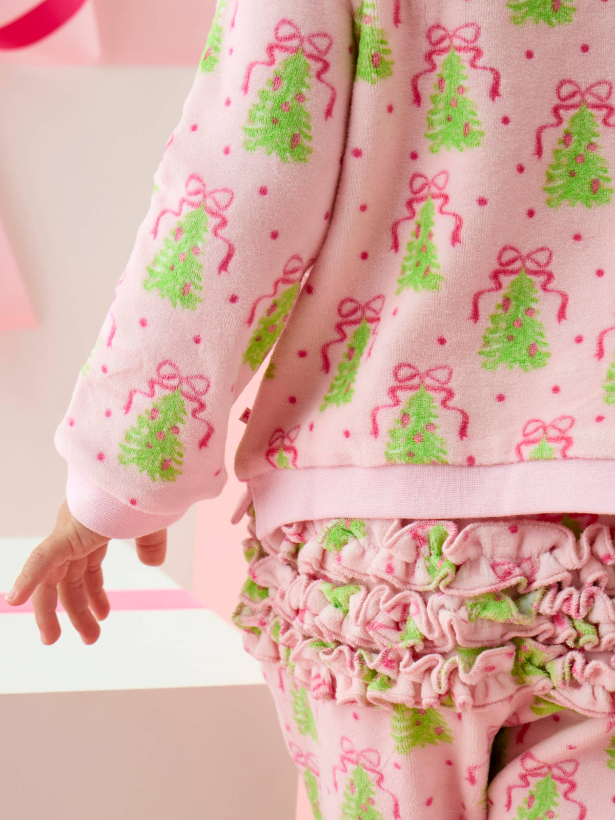 Close up of fabric patterned with Christmas Trees with pink bows