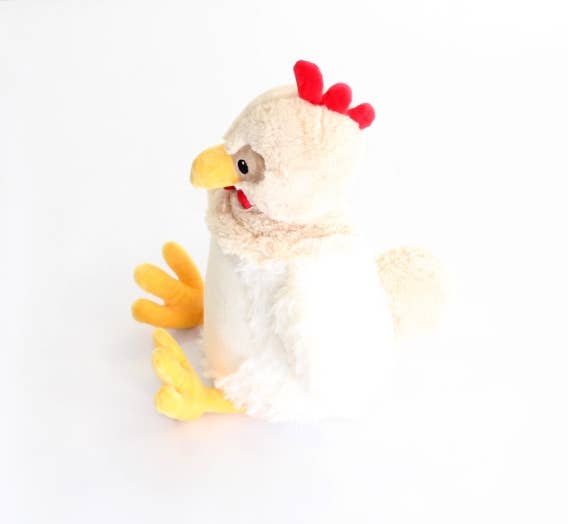 Plush chicken with red comb against white background. 