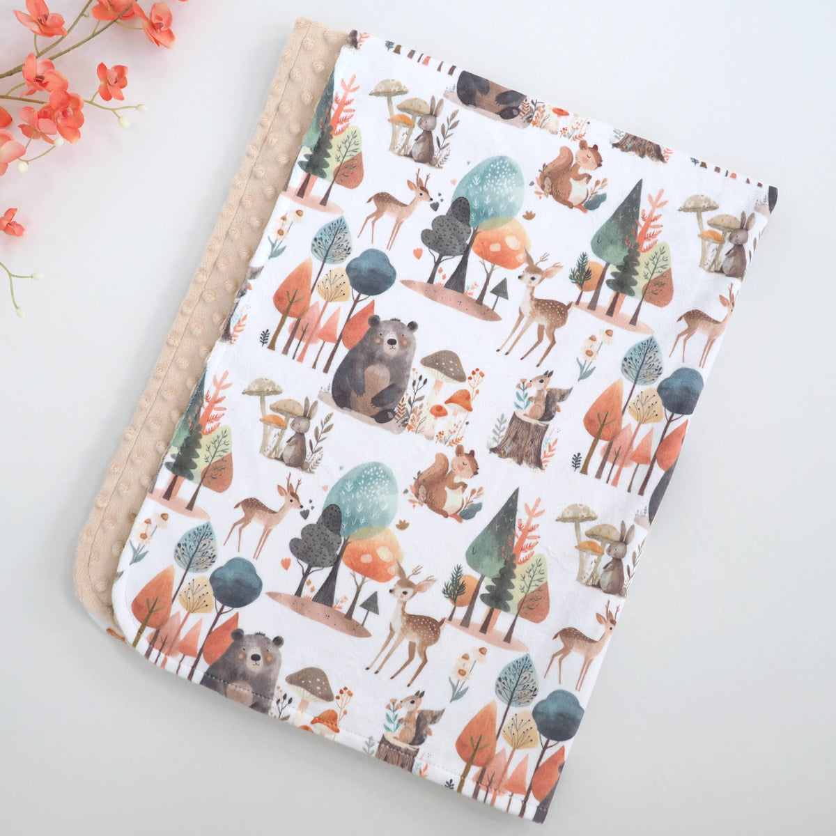 Close up of enchanted forest themed blanket on a white background with a tan reverse side