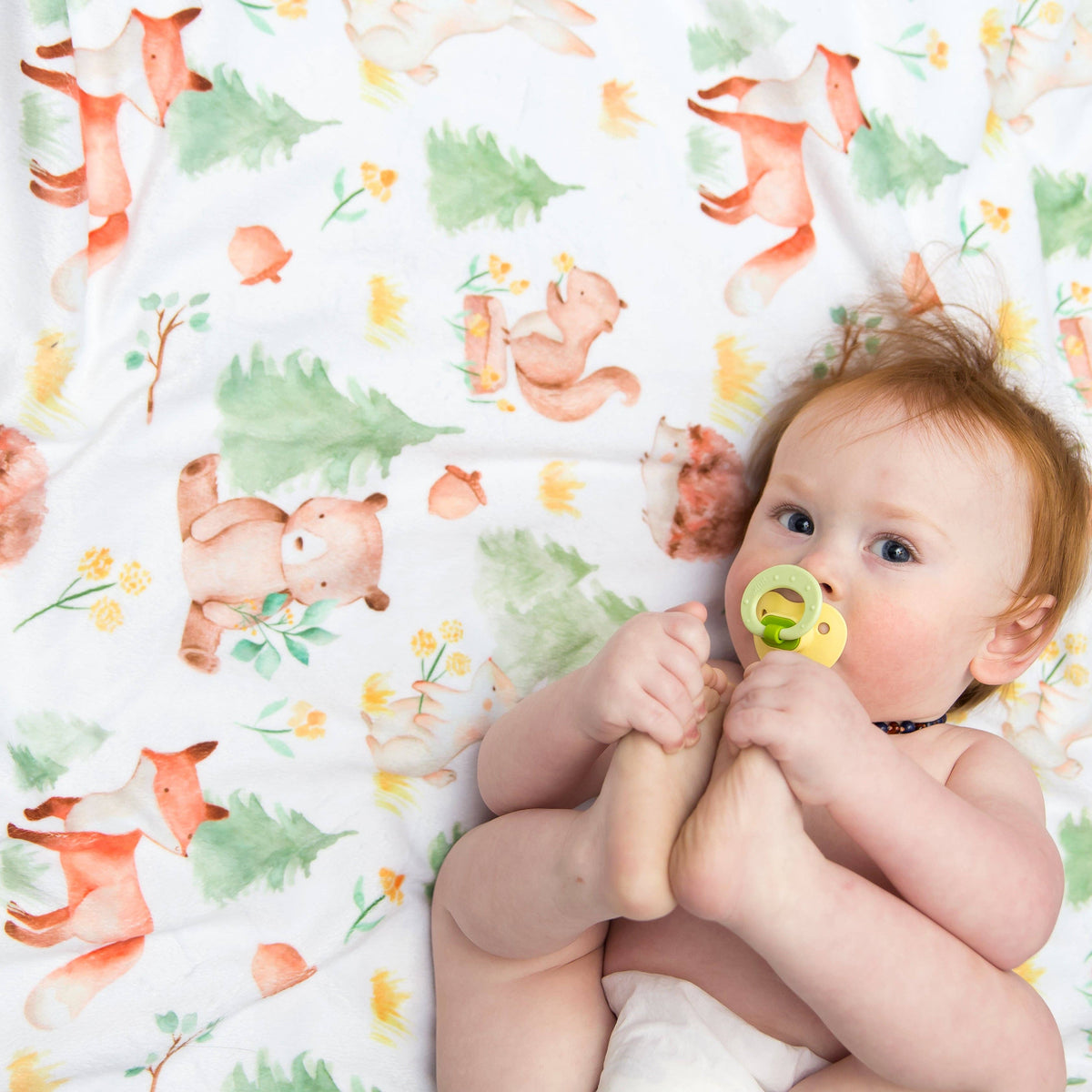 Baby on a Blanket with a forest theme showing pine trees and bears, foxes, and bunnies on a white background