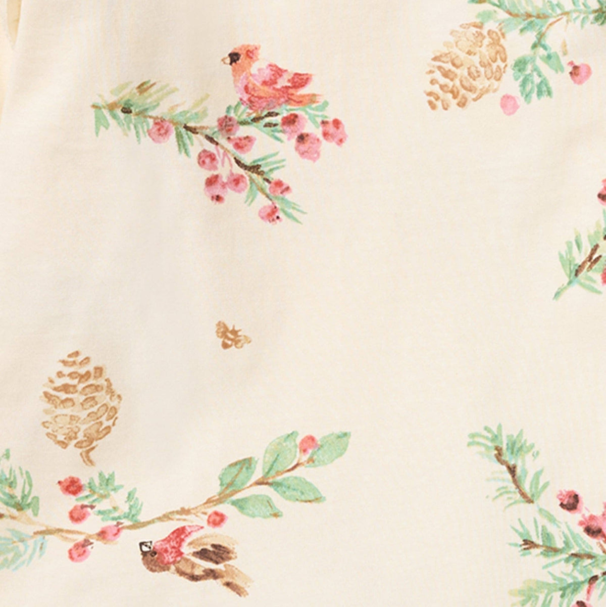 Close up of cream fabric with cardinals sitting on pine branches. 