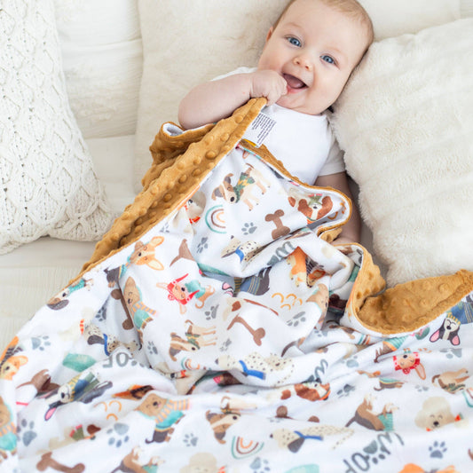 Minky blanket with cozy winter dog pattern over a baby perched on a couch