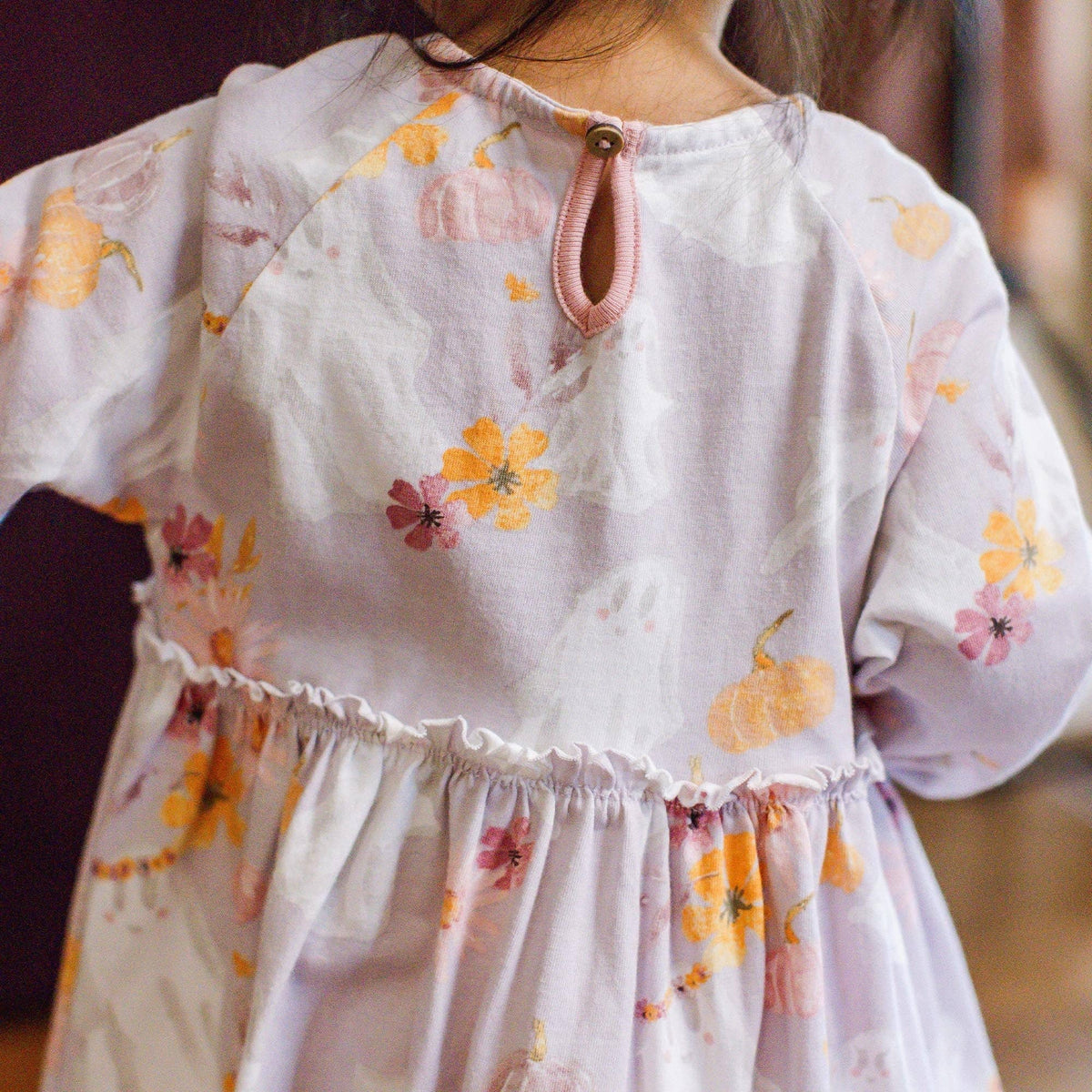 Floral dress with puff sleeves worn by a child, blurred background